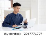 Small photo of Young asian man calculating finance household with calculator on desk at home, male checking bill and success for saving expenses household, debt closure, tax and accounting, business concept.