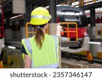 Young caucasian engineer woman or worker pointing and checking electric train for planning maintenance in station, transport and infrastructure, inspector check service transport, rear view.