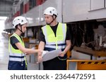 Young caucasian engineer man and woman or worker look blueprint and checking electric train for planning maintenance in station, transport and infrastructure, inspector or technician check transport.