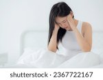 Small photo of Young asian woman sitting on bed pain headache in the bedroom at home, unhappy female exhaustion and sick headache, anxiety and unwell, dizziness and disorder, medical and health concept.