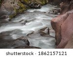 Small photo of Mountain river flowing through the narrow canyon with missive, colorful rocks covered by golden, sunlit moss during autumn