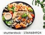 Roasted Mixed Seafood Contain Mussels, prawns, salmon, Calamari Squids and Grilled Barracuda Fish Garlic with Spicy Chili Sauce. Isolated on White Background. Seafood and meat platter. Mediterranean