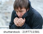 Small photo of Middle aged handsome man in cold day outdoors.Too cold. Concept of leisure time, cold weather during winter season. He's trying to wrap himself up. Portrait, front view. Close up. Walking without hat.