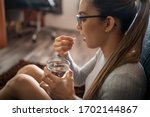 Small photo of Side View of A Young Sick White Woman at Home Swallowing Her Medical Treatment Pills With a Glass of Water. Concept of Medicine, Drugs Adherence, Antibiotics and Pain Killer Addiction.