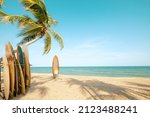 Surfboard and palm tree on beach with beach sign for surfing area. Travel adventure and water sport. relaxation and summer vacation concept. vintage color tone image.