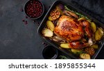 Roasted chicken in pomegranate sauce with potatoes in a gray ceramic mold. Dark background. Top view. Copy space