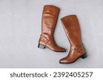 Boots. Women's brown leather high long boots on gray background. Top view.