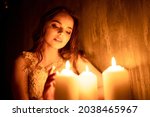 Small photo of A woman is sitting in a room by candlelight. A young girl looks at burning candles and wonders at her betrothed