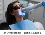 Small photo of Close-up portrait of a female patient at dentist in the clinic. Teeth whitening procedure with ultraviolet light UV lamp.