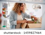 View Looking Out From Inside Of Refrigerator As Woman Unpacks Online Home Food Delivery