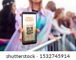 Close Up Of Woman Holding Mobile Ticket On Screen To Camera As She Arrives At Entrance To Music Festival
