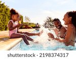 Family On Summer Holiday With Two Girls Eating Ice Lollies By Swimming Pool Splashing Parents