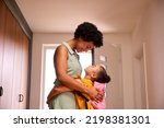 Daughter At Home Hugging Mother As She Helps Her To Get Ready For School