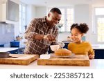 Family Shot With Father And Daughter Baking At Home In Kitchen Decorating Cake With Icing