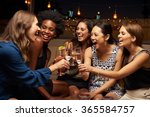Group Of Female Friends Enjoying Night Out At Rooftop Bar