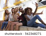 Five friends sitting on a wall in Ibiza taking a selfie
