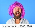 Funny bearded man in wig. Handsome bearded man with mustache in wig. Fashion concept. Barbershop. Hipster in periwig. Happy stylish man with pink hair.