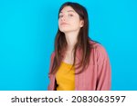 Small photo of Young caucasian girl wearing casual clothes isolated over blue background with snobbish expression curving lips and raising eyebrows, looking with doubtful and skeptical expression, suspect and doubt.