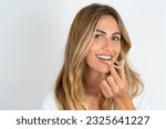 Young beautiful caucasian woman over white background holding an invisible aligner ready to use it. Dental healthcare and confidence concept.