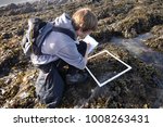 Small photo of Student on a field trip. Using Quadrate on a rocky shore looking at seaweed coverage.