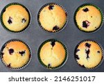 Summer baking - delicious homemade muffins with black currant in colorful paper moulds in baking tray, top view, close up 