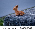 Lost stuffed animal that looks like a bamby toy sitting on a stone