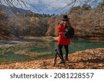Back view of female photographer in red jacket and black hat taking photos in sevenlakes (yedigoller), Bolu, Turkey 