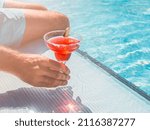 Beautiful glass with a refresh cocktail and an attractive man on the background of the swim pool. Top view, close-up. Vacation and travel concept. Moments of celebration