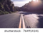 Small photo of Unknown street, road less traveled, yellow road paint in the woods or outdoor area. Sunny with black paved road. Road goals to get somewhere.