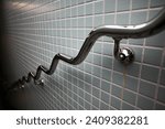 Small photo of Wobbly chrome handrail on tiled subway wall.Metal Chrome Steel Handrail Public Staircase Safety.Tokyo,Japan