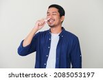 Adult Asian man showing relieved expression when using nasal stick inhaler