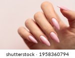 Female hand with a beautiful light pink manicure on a light background, blank space