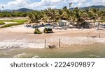 Small photo of Vieux Fort, Saint Lucia - 10-16-2022: Drone shot following a tractor picking up sargasso seaweed on the beach.