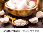 Small photo of wooden spoon with ground eggshells, used white eggshell prepared for use as fertilizer, leftover food