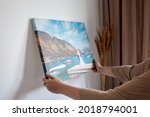 Small photo of Canvas print with gallery wrap. Woman hangs wedding photography on white wall. Hands holding photo canvas print
