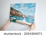Small photo of Canvas print with gallery wrap. Woman hangs wedding photography on white wall. Hands holding photo canvas print