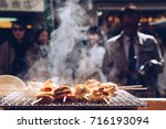 grilled seafood scallop and sea urchin eggs skewer with smoke, japanese street food at Tsukiji Fish Market, Japan. selective focus and film style.