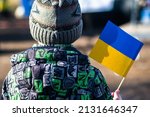 Small photo of Child or kid with winter clothes, hat and Ukrainian flag, profile of the child is on the flag. War in Ukraine, caused by Putin and Russia, refugee, refugees camp