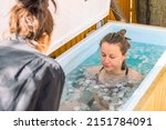 Small photo of Vilnius, Lithuania - April 30 2022: Girl or woman ice bathing in the cold water among ice cubes with instructor. Wim Hof Method, cold therapy, breathing techniques, yoga and meditation