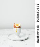 Small photo of Soft-boiled egg in eggcup with yolk on white stone table.