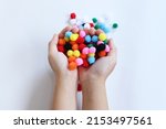 Woman's hand holding colorful fluffy Pom Poms for sewing. Bright fur ball for decoration.