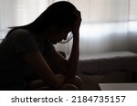 Depressed woman sitting alone on the bed with hands on head feel stress, sad and worried in the dark bedroom and low light environment