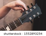 guy tuning his guitar. Guitar neck and tuning pegs