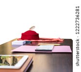 Small photo of African business man's table showing his redcap with feather, beaded necklace, jotter, pink file, wooden pen, documents, tablet and diary. Suitable for websites, magazines and social media.