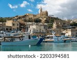 Small photo of Mgarr, Gozo - September 13th 2022: Fishing boats and the AFM search and rescue launch Melita II moored in Mgarr Harbour overlooked by the Church of Our Lady of Lourdes.