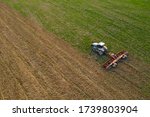 Side view of an aircraft flying over a field cultivated by a crawler tractor during a crisis in the agro-industrial sector