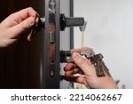 Small photo of Installation of a lock and door handle to an interior door, a locksmith works with the door, the keys are in the door lock.