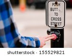 A man pushing a crosswalk button that reads, 