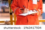 Small photo of Action of safety officer is wirtinng and check on checklist document during safety audit and inspection at drilling site operation. Industrial expertise occupation photo.
