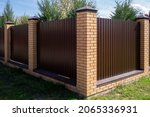 A Brown Metal Fence With Brick...